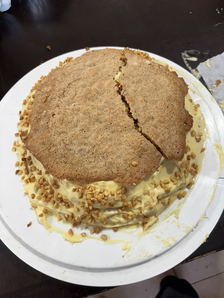 Stacking the meringue layers with custard and chopped peanuts on the sides