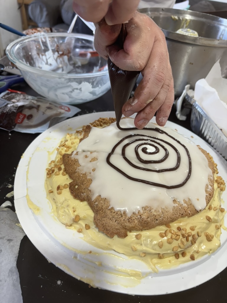 Piping a chocolate fondant spiral onto the white top